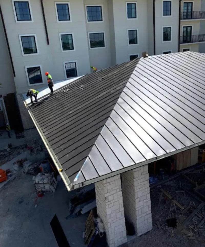 Crew installing standing seam metal roof panels on a commercial project in Anderson